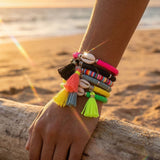 Colorful bracelets with tassels on a wrist against a beach sunset background