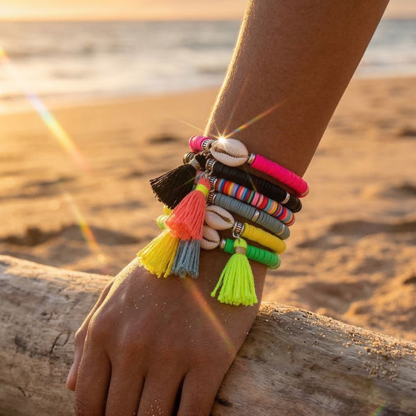 Colorful bracelets with tassels on a wrist against a beach sunset background