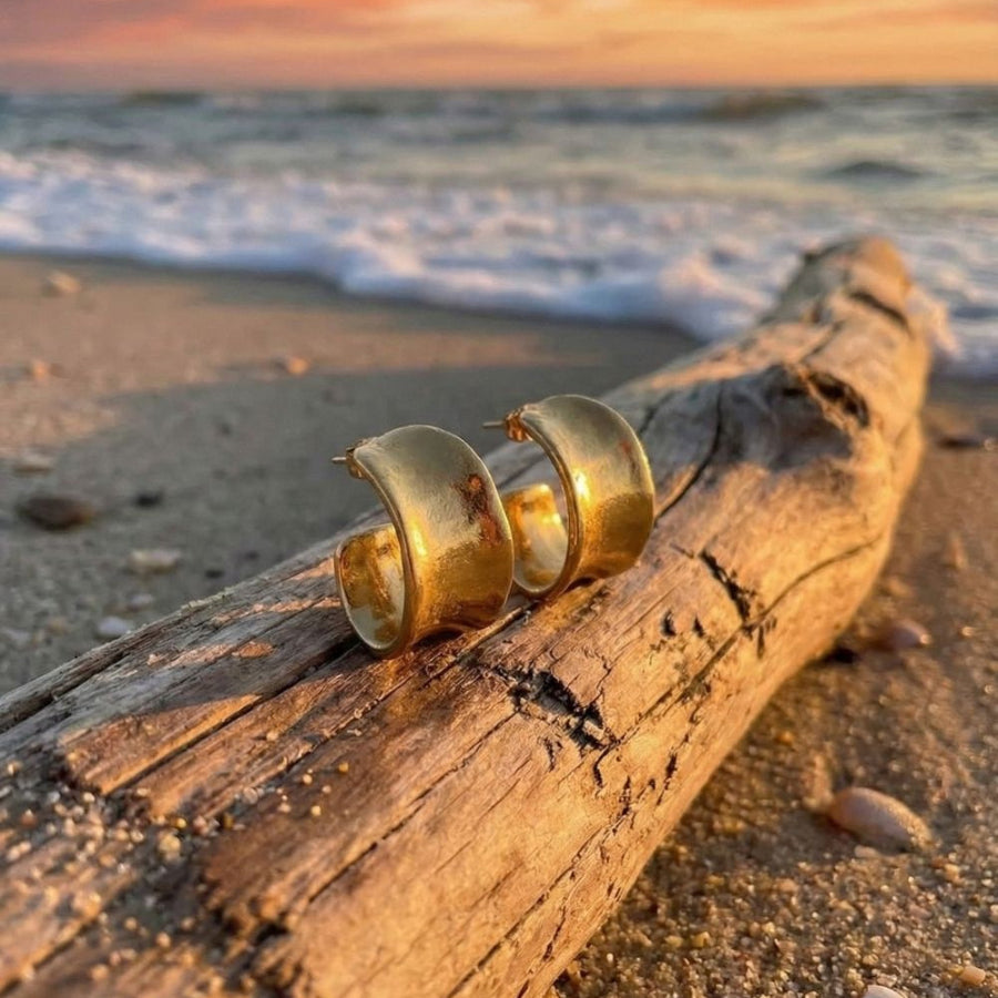 golden silver sterling hoops on drift wood on the beach