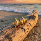 golden silver sterling hoops on drift wood on the beach