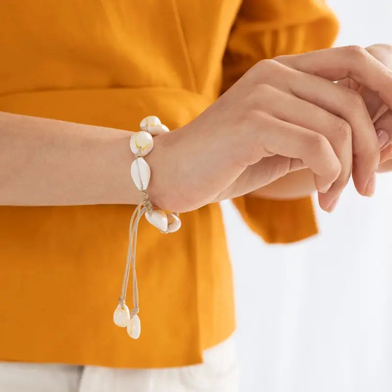 white cowrie bracelet aon a woman wrist