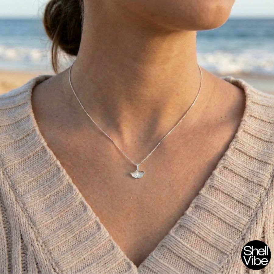 Woman wearing a sterlilng silver necklace with a silver seawead pendant by the sea.