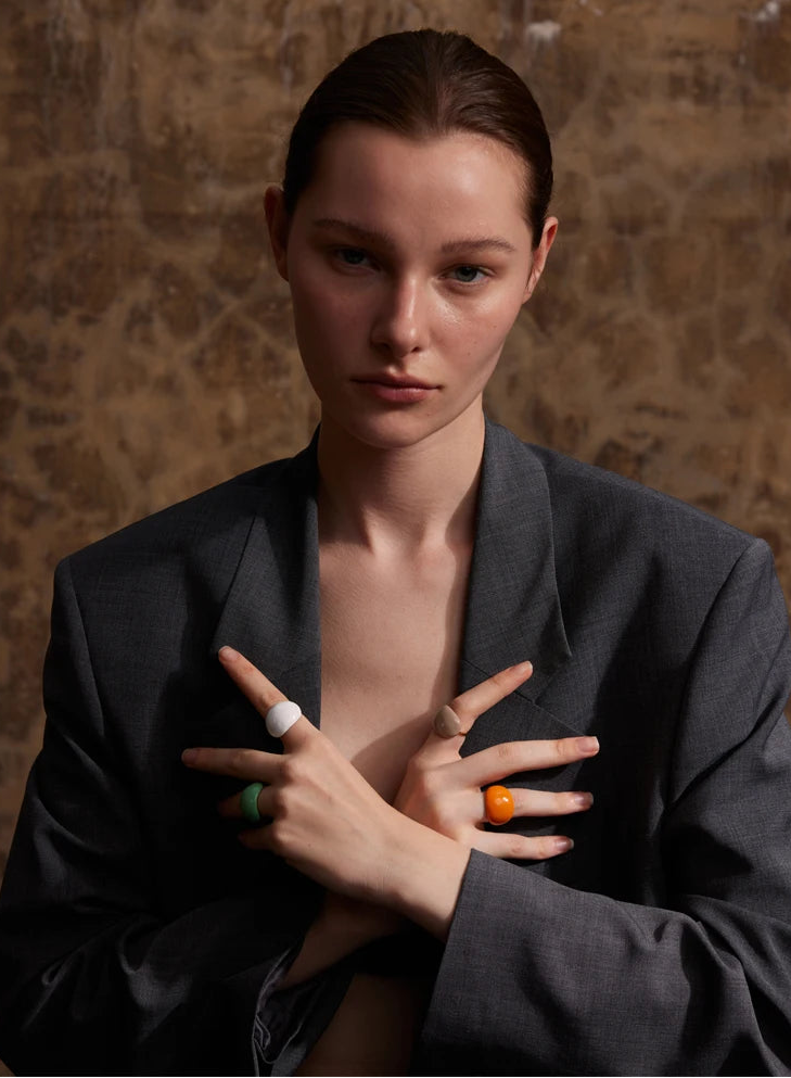 “Model wearing multiple colorful enamel dome rings on both hands, styled with a dark blazer.”
