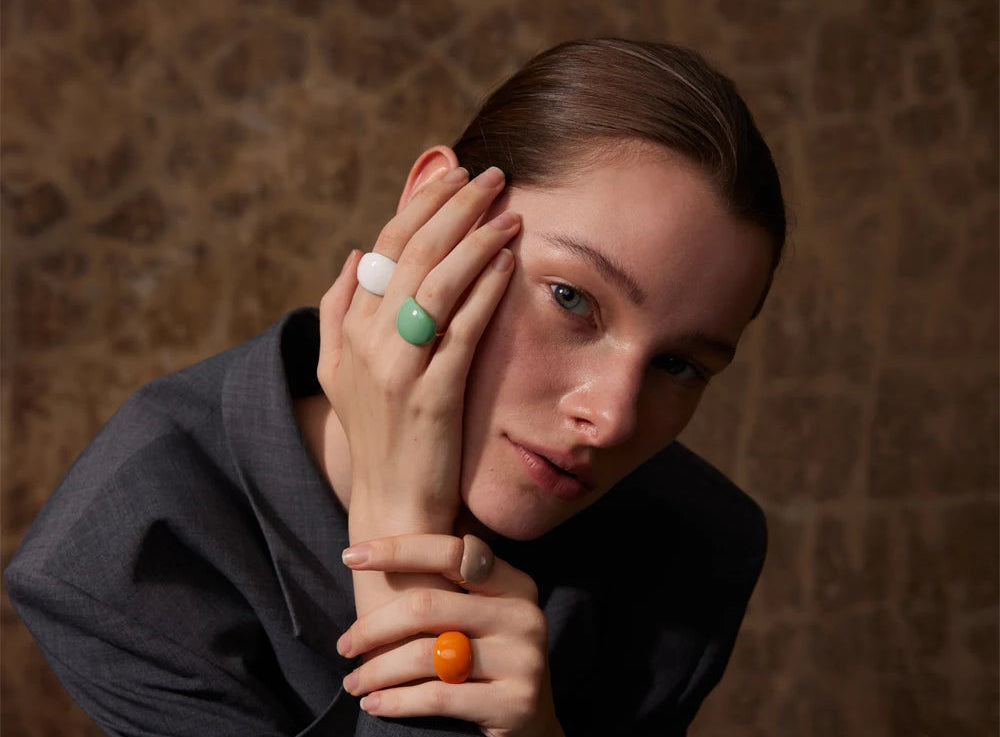 Woman with rings on her fingers against a textured brown background