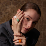 Woman with rings on her fingers against a textured brown background