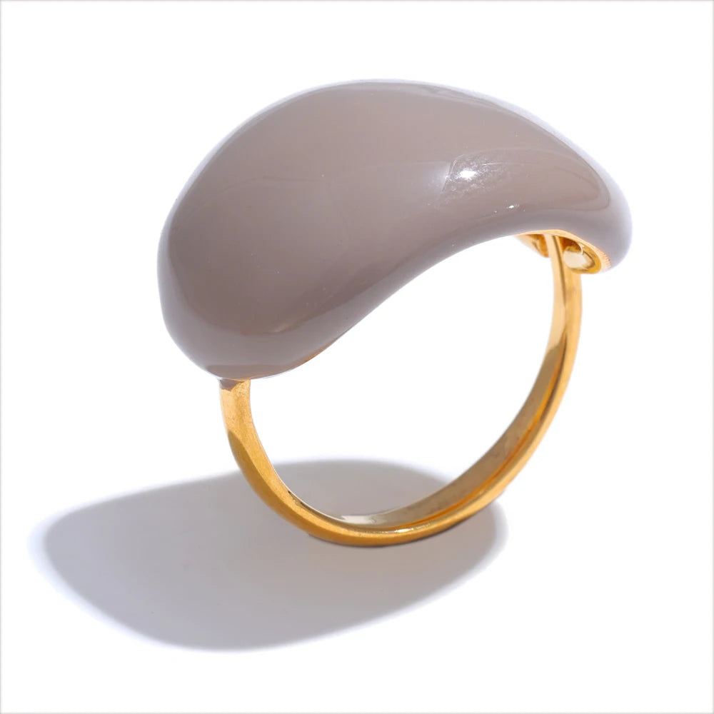 Ring with a large beige stone and gold band on a white background
