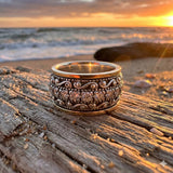Decorative silver ring on a wooden plank with a sunset over water in the background