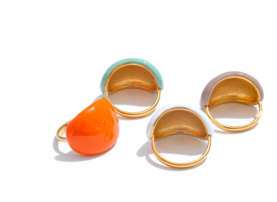 Set of three gold-rimmed rings with colorful stones on a white background