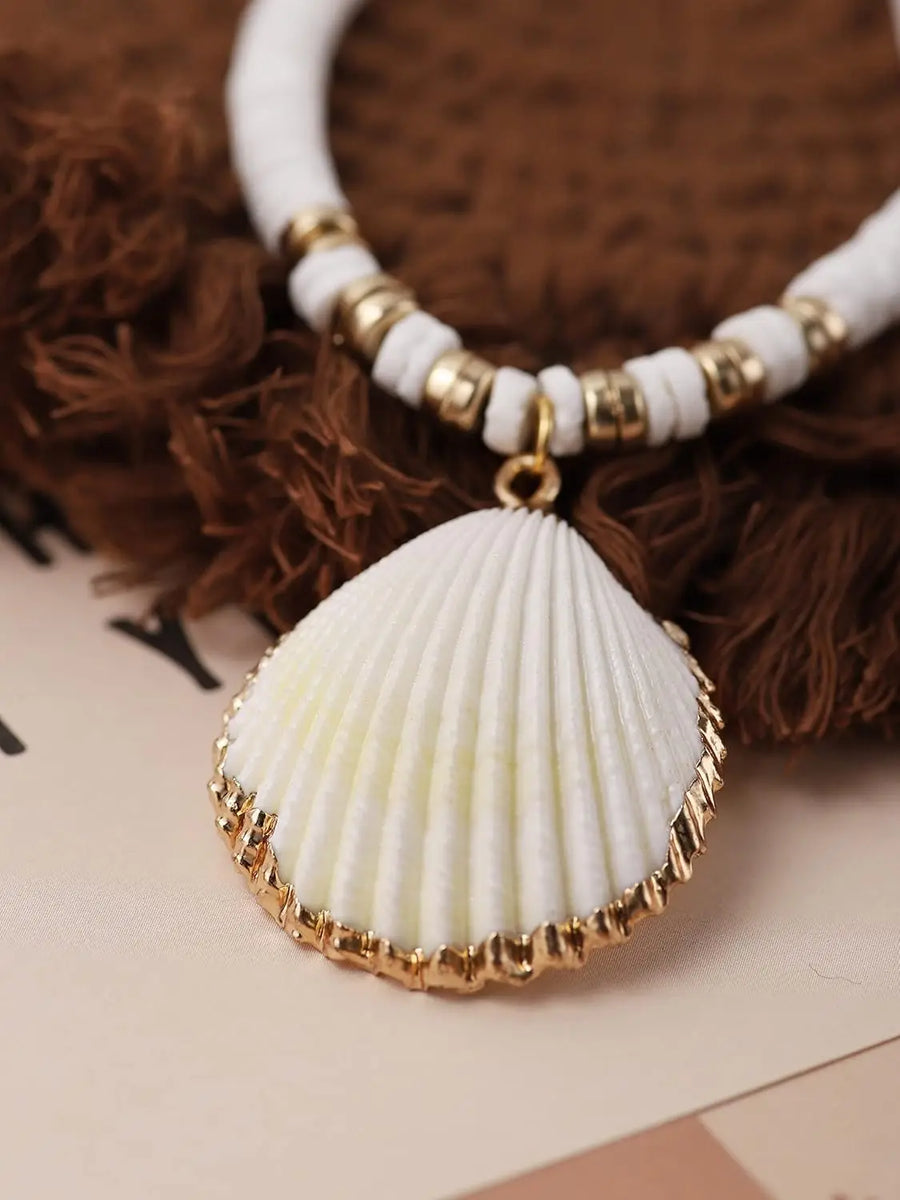 Necklace with a shell pendant and white beaded chain on a brown textured surface