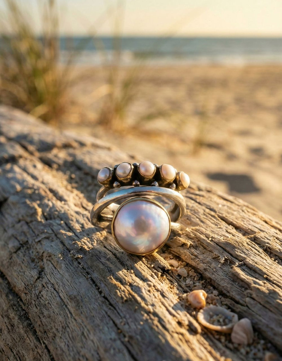 Sterling silver Pearl ring on a piece of driftwood with a beach background