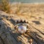 Sterling silver Pearl ring on a piece of driftwood with a beach background